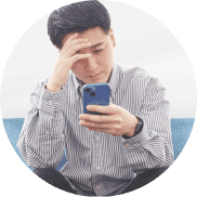 スマホを見ながら頭を抱える男性